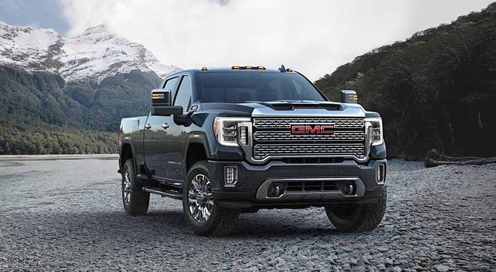 A grey 2020 used GMC Sierra 2500 for sale is shown parked on the rocky shore next to a river.