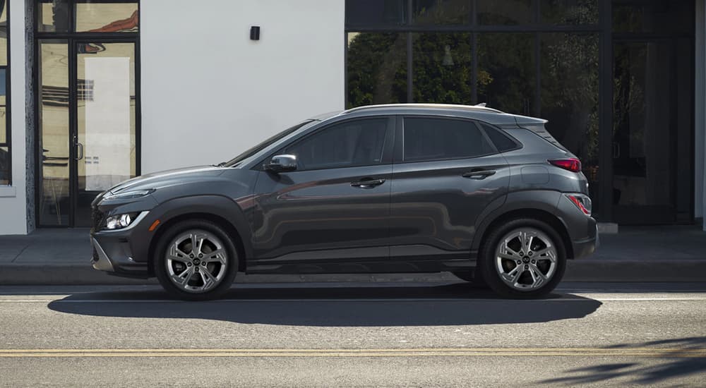 A grey 2022 Hyundai Kona is shown from the side parked next to a white building.