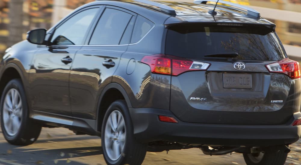 A grey 2013 Toyota RAV4 is shown from the rear driving on a road.