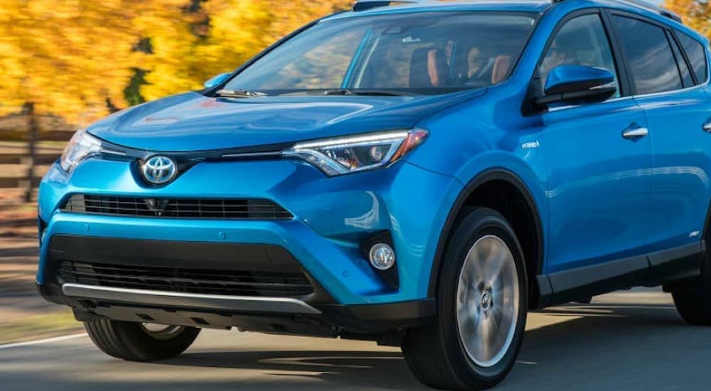 A blue 2016 Toyota RAV4 is shown driving on a road after viewing used SUVs for sale.