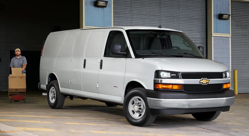 A white 2022 Chevy Express is shown parked outside of a warehouse.