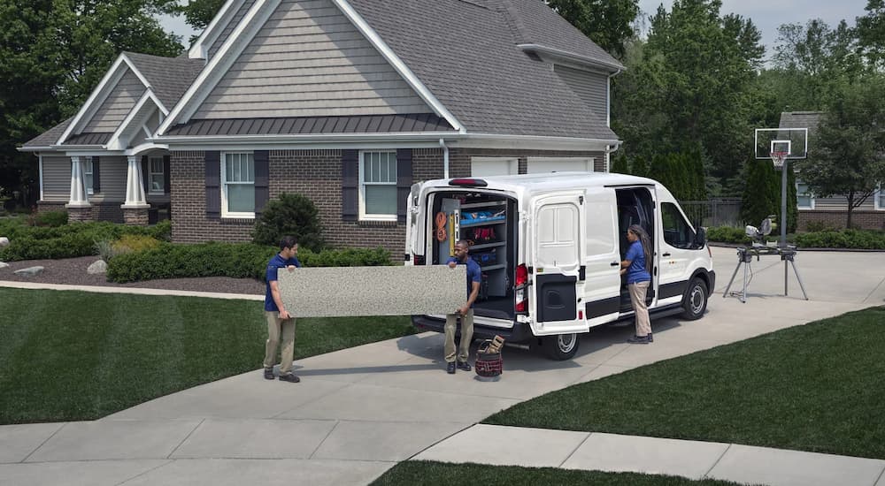 A group of people are shown taking cargo out of a white 2022 Ford Transit van.