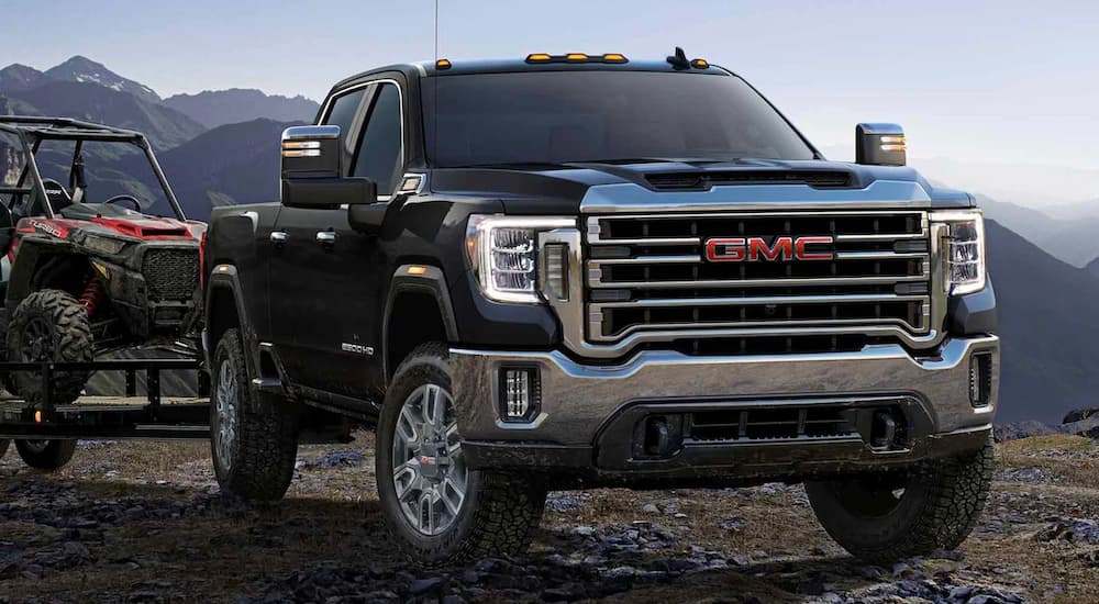 A black 2022 Chevy Sierra 2500 HD is shown towing an ATV after viewing diesel trucks for sale.