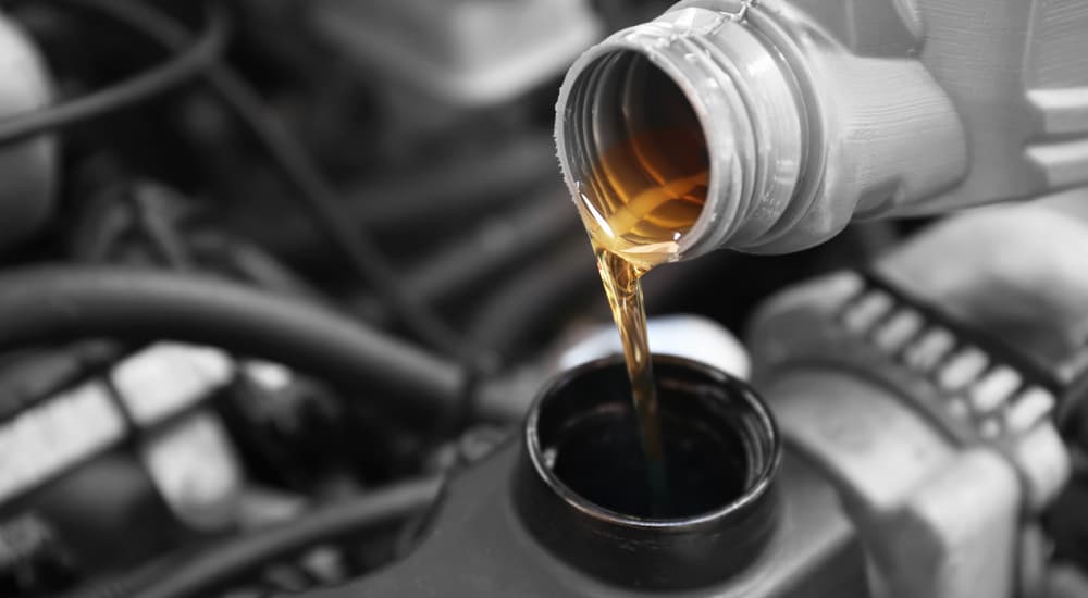 A bottle of oil is shown being poured into an engine.