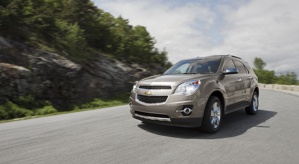 A tan 2012 Chevy Equinox LTZ is shown driving on an open road.