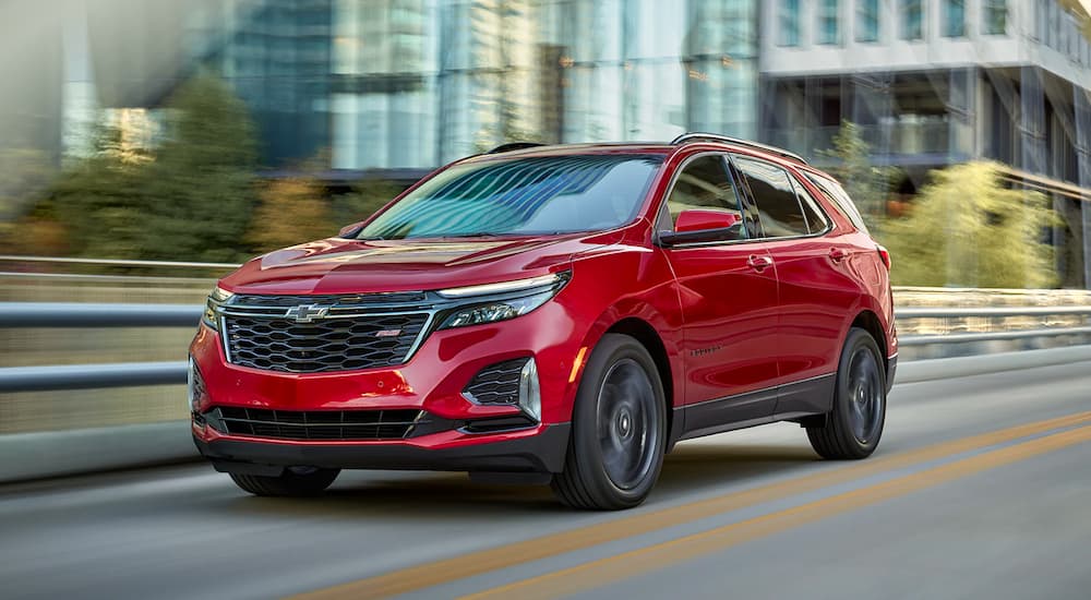 A red 2023 Chevy Equinox RS is shown driving on a city street.
