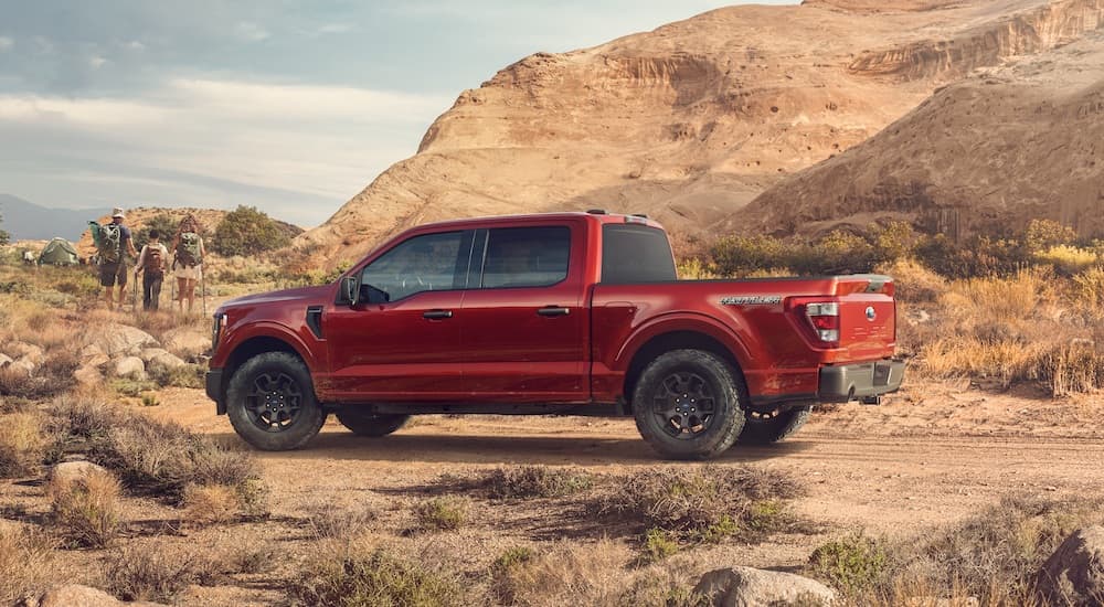 A red 2023 Ford F-150 Rattler is shown from the side while parked off-road during a 2023 Ford F-150 vs 2023 Chevy Silverado 1500 comparison.