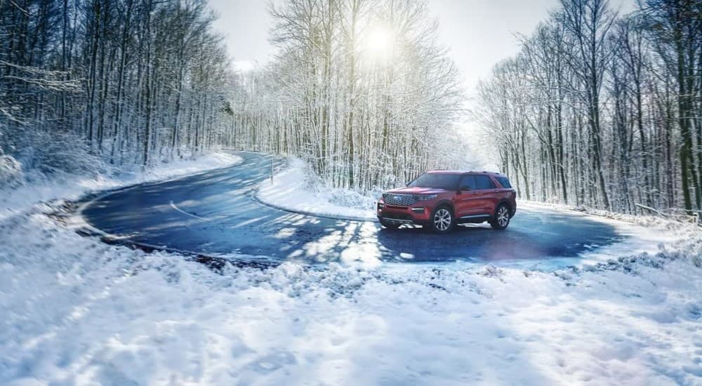 A red 2023 Ford Explorer is shown rounding a corner on a snowy road.