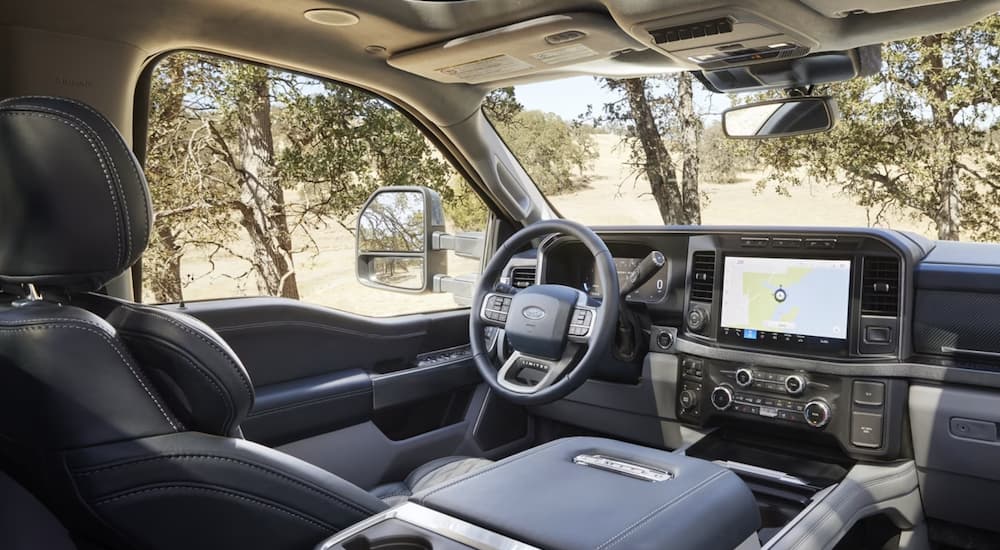 The black interior of a 2023 Ford F-350 shows the steering wheel and infotainment screen.