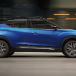 A blue 2023 Nissan Kicks is shown from the side driving on an open road.