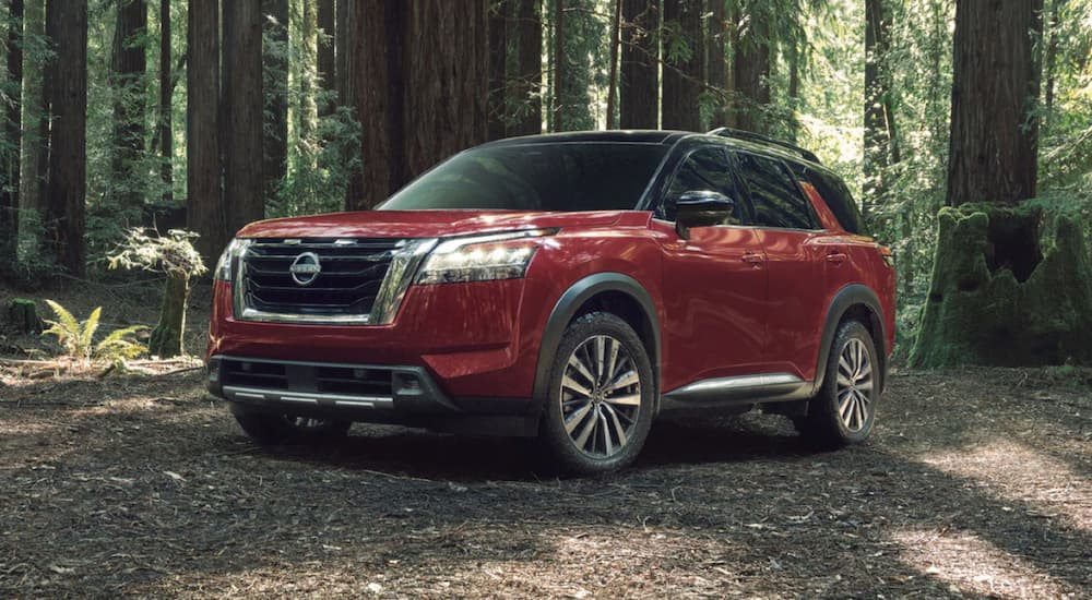 A red 2023 Nissan Pathfinder is shown from the side parked in the woods.