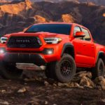 An orange 2023 Toyota Tacoma TRD Pro is shown parked on a rocky path.