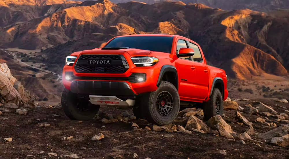 An orange 2023 Toyota Tacoma TRD Pro is shown parked on a rocky path.