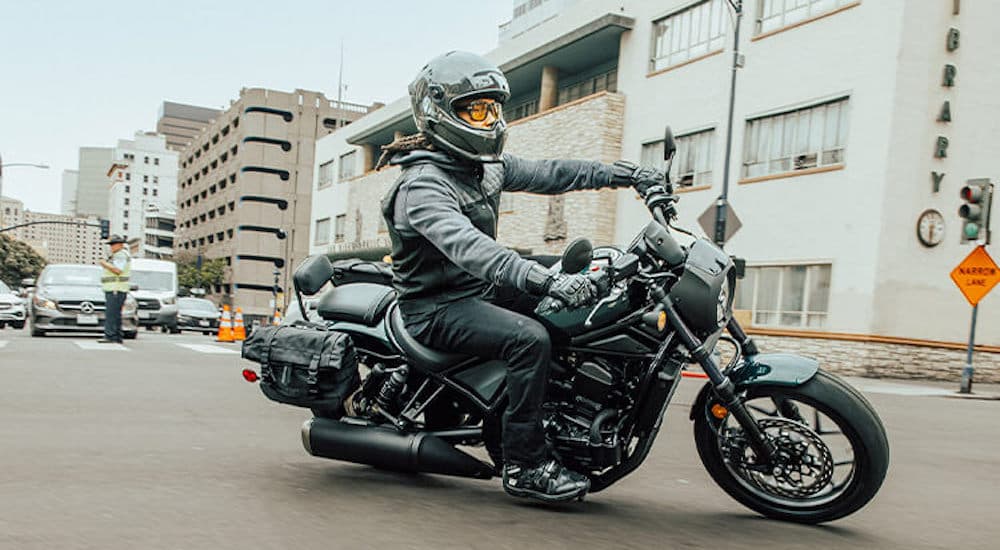 A gray 2023 Honda Rebel 1100 is shown from the side while cornering.