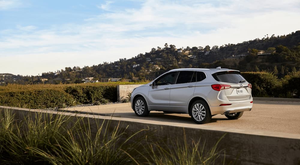 A silver 2019 Buick Envision is shown from a rear angle while parked in a driveway.