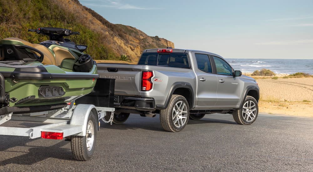 A grey 2023 Chevy Colorado Z71 is shown towing a jetski near the ocean.