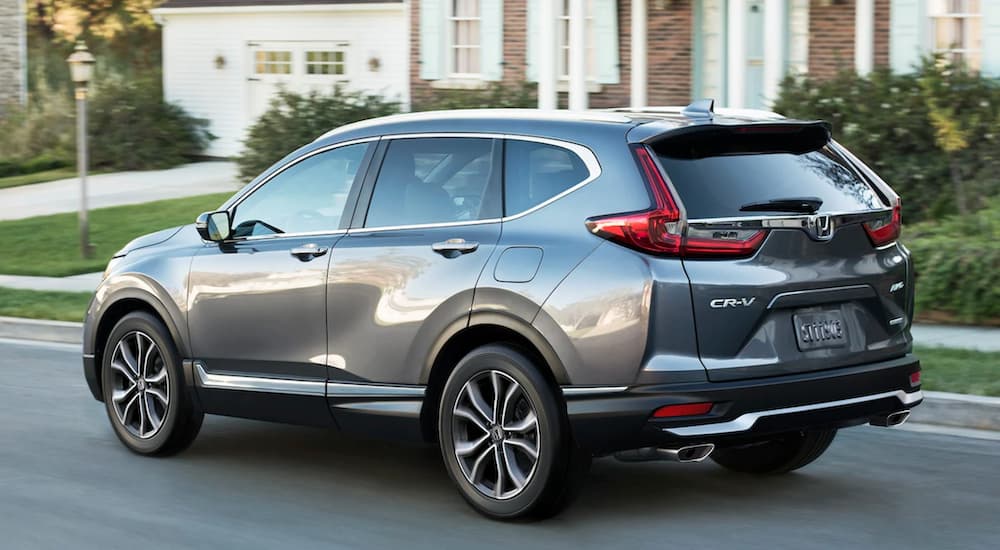 A grey 2022 Honda CR-V for sale is shown driving on a suburban street.