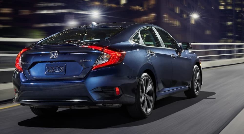 A dark blue 2020 Honda Civic is shown driving on a city street at night.