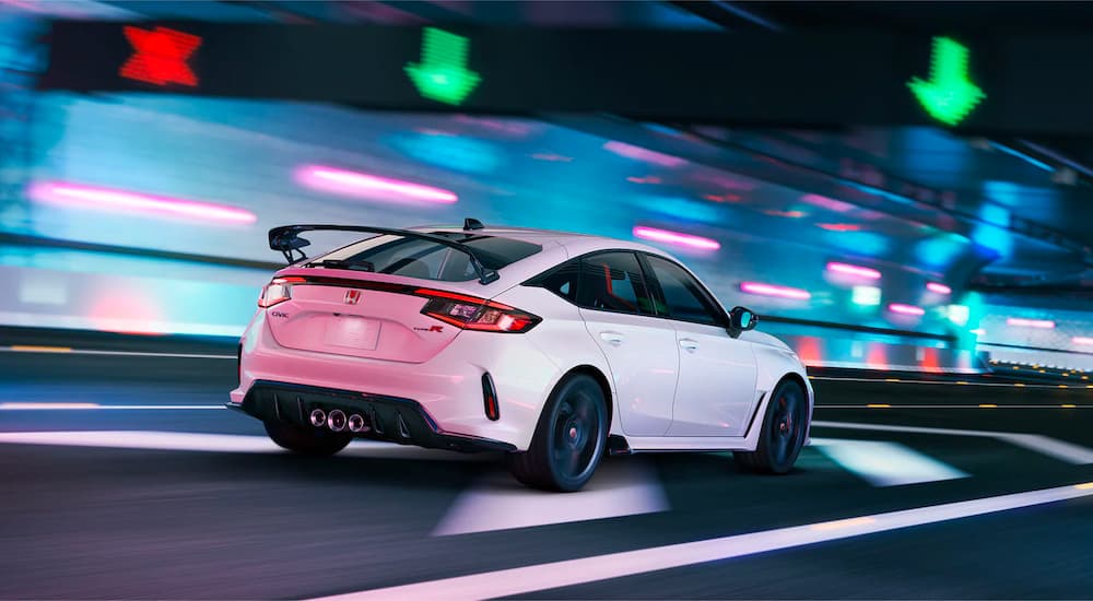 A white 2023 Honda Civic Type R is shown driving on a highway after visiting a Honda dealer.