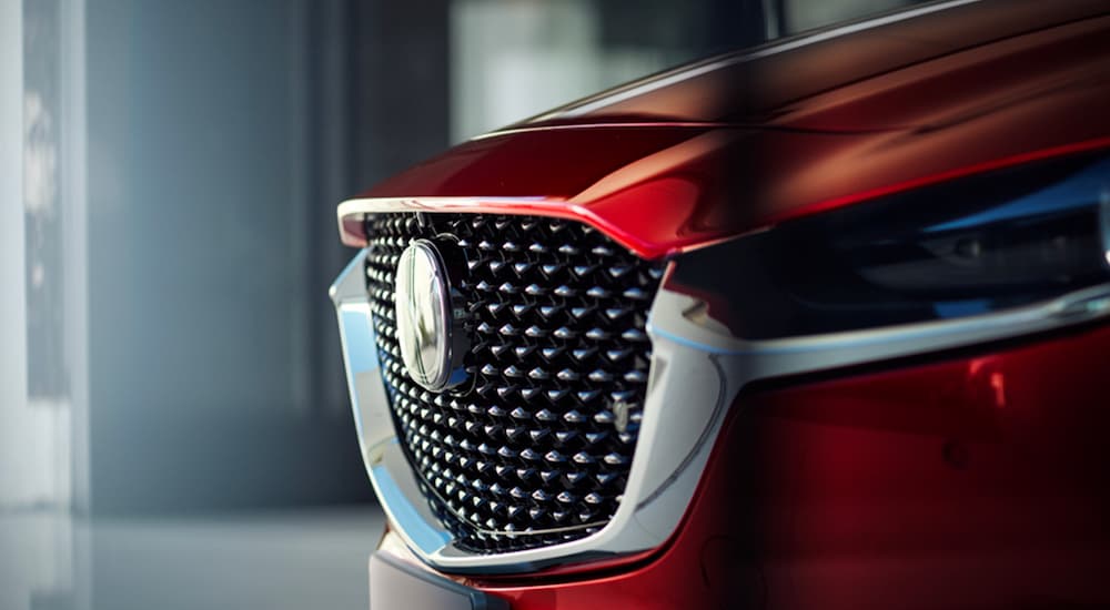 A close up shows the grille of a red 2023 Mazda CX-30 at a Mazda dealership.