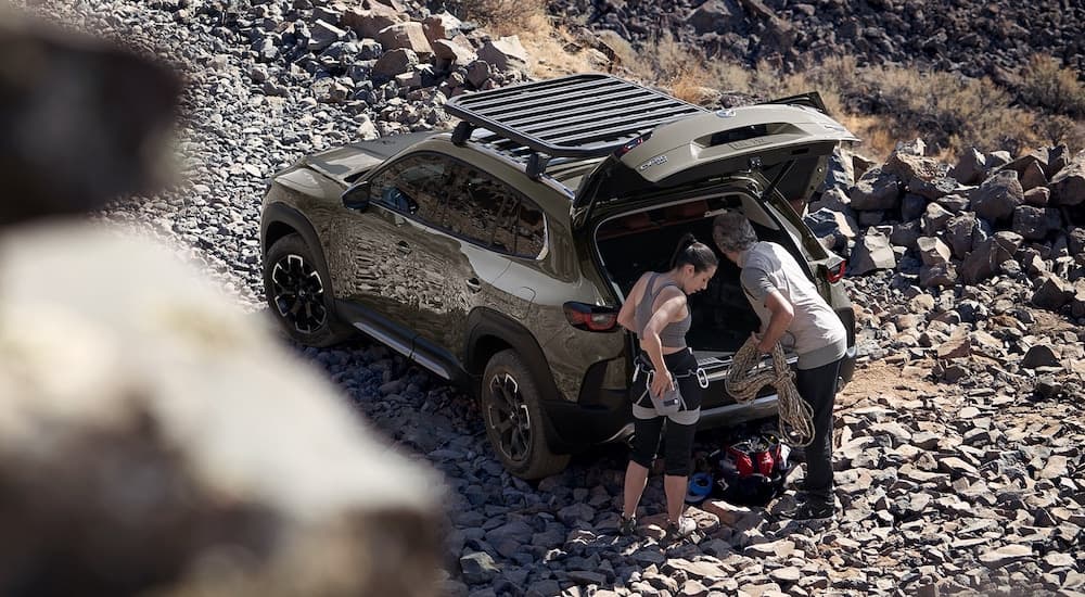 A green 2023 Mazda CX-50 is shown on a rocky trail at a high angle.