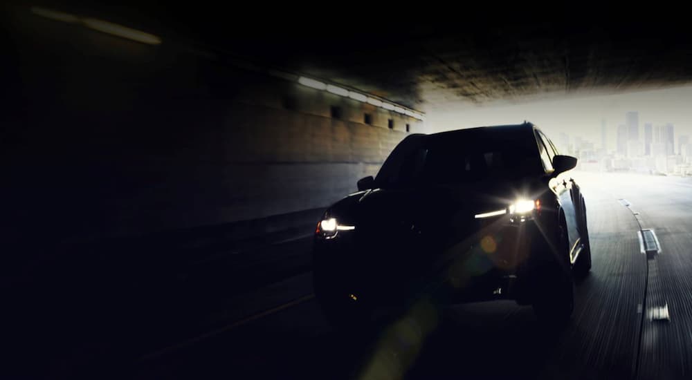 A black 2024 Mazda CX-90 is shown driving through a tunnel.
