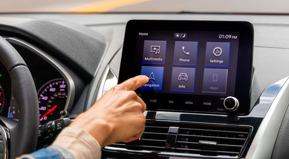A person is shown selecting an app in a 2023 Mitsubishi Eclipse Cross. 