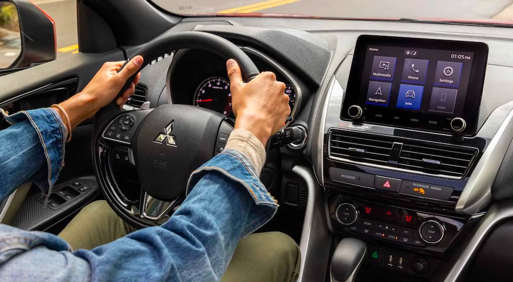 A person is shown steering a 2023 Mitsubishi Eclipse Cross for sale.