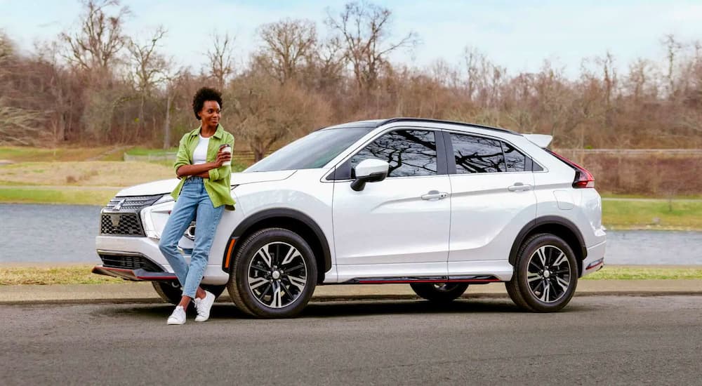 A person is shown leaning against a white 2023 Mitsubishi Eclipse Cross.