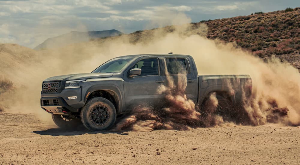 A grey 2023 Nissan Frontier is shown off-roading.