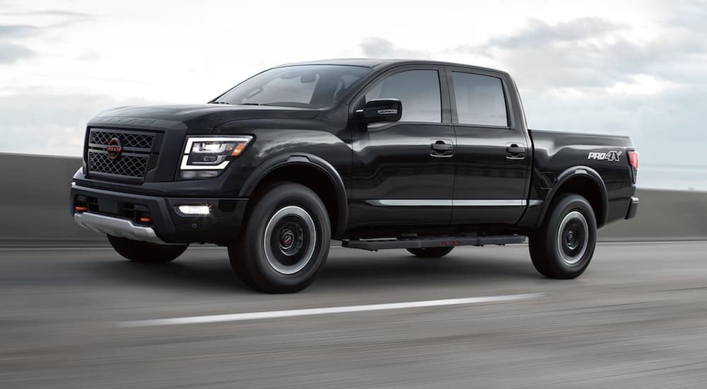 A black 2023 Nissan Titan is shown from the side driving on an open road.