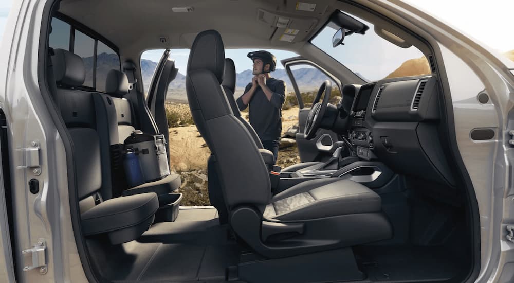 The black interior of a 2023 Nissan Frontier SV shows the cab from the side.