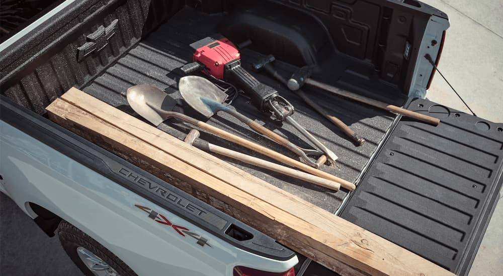 Various tools and supplies are shown in the bed of a white 2023 Chevy Silverado service truck for sale.
