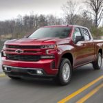 A red 2019 Chevy Silverado 1500 RST is shown driving past a lake.