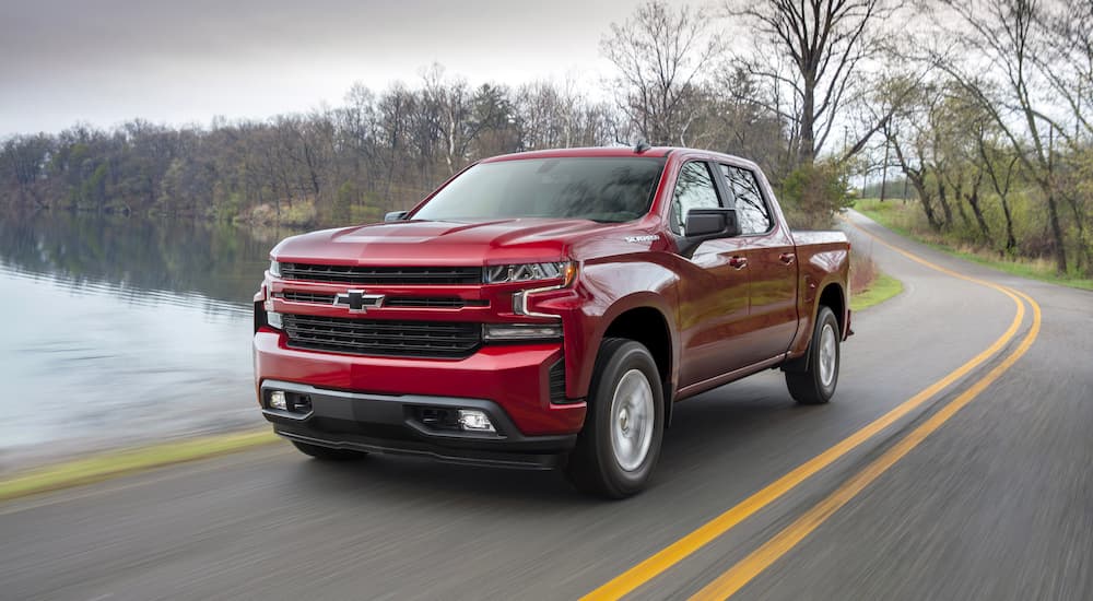 A red 2019 Chevy Silverado 1500 RST is shown driving past a lake.