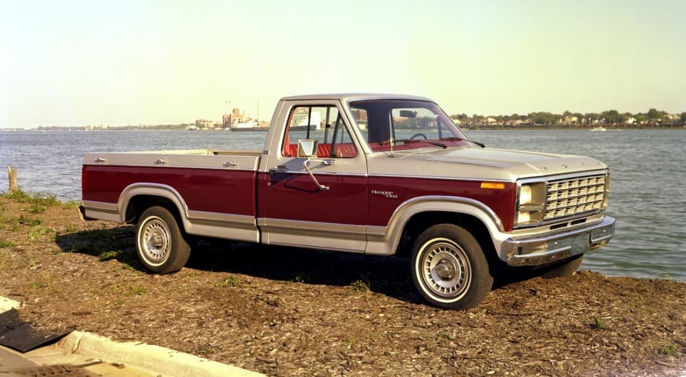 An old used Ford truck near you, a red 1980 Ford F-100, is shown parked near the ocean. 