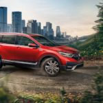 A red 2021 Honda CR-V is shown driving on a path near a city.