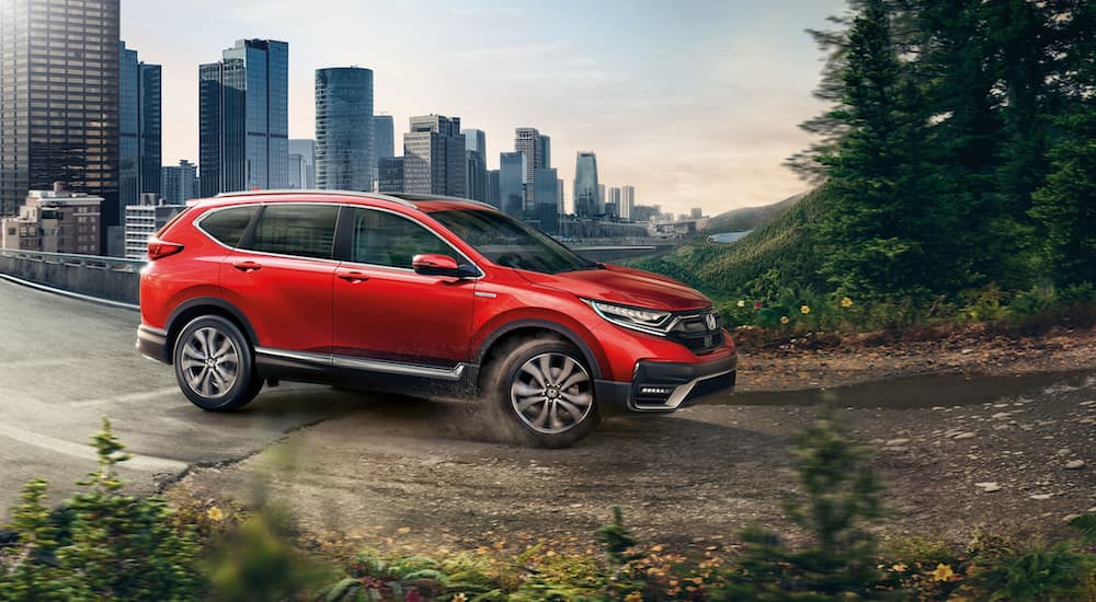 A red 2021 Honda CR-V is shown driving on a path near a city.