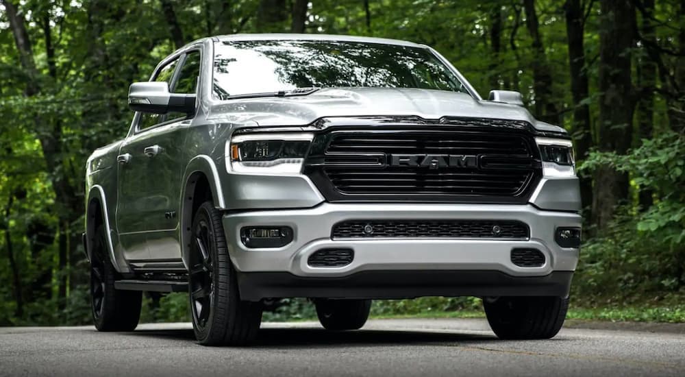 A grey 2020 Ram 1500 is shown from the front driving on an ope road through the woods.