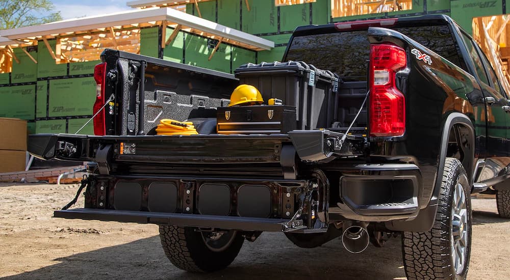 A black 2023 Chevy Silverado 2500 HD is shown from the rear with construction supplies in the bed.