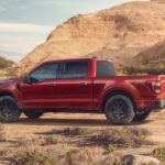 A red 2023 Ford F-150 Rattler is shown from the side while off-road.