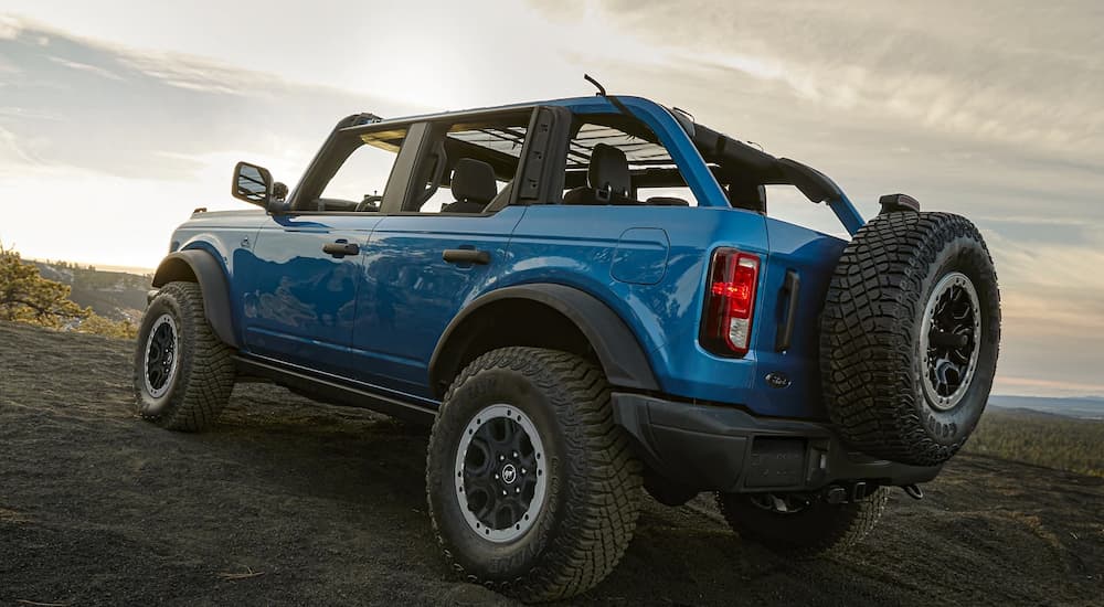 A blue 2023 Ford Bronco Black Diamond is shown from a rear angle driving on an open dirt lot.