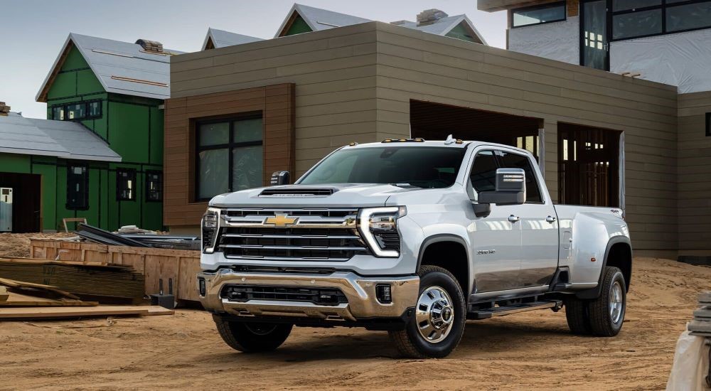 A white 2024 Chevy Silverado 2500HD is shown on a dirt driveway.