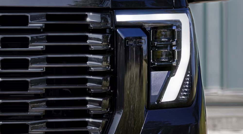 A close up of the headlight on a black 2024 GMC Sierra 2500 HD Denali Ultimate is shown.