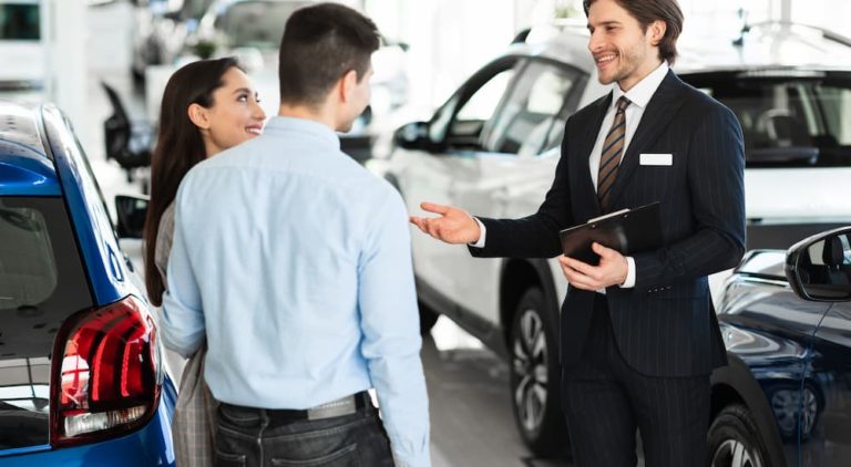 A salesman is shown speaking to a couple about bankruptcy auto loans.