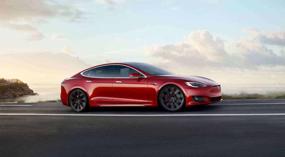 A red 2020 Tesla Model S is shown driving on a road. 
