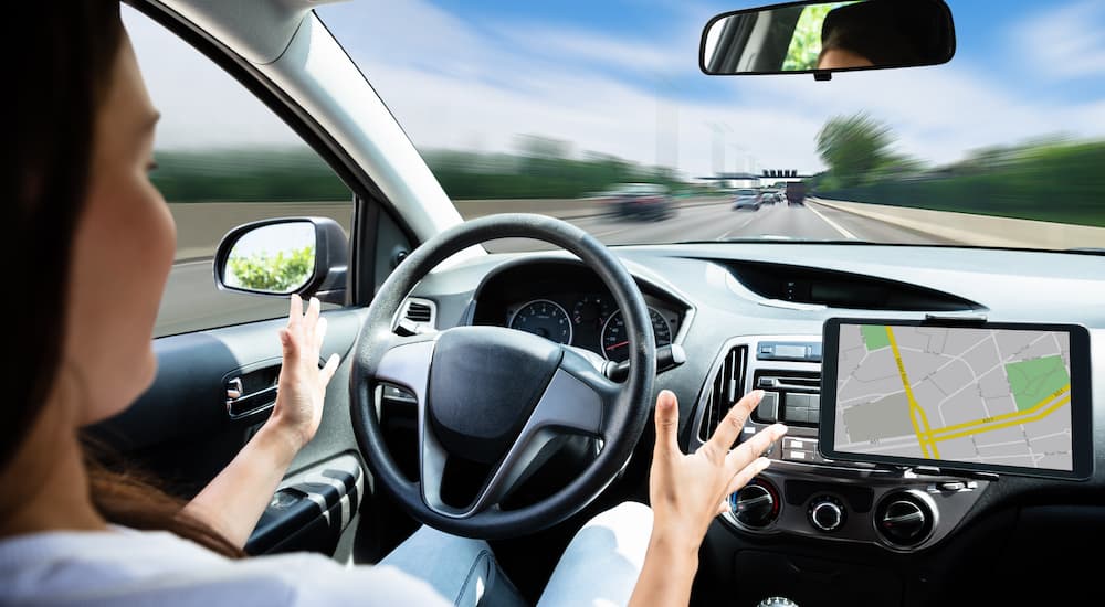 A woman is shown with her hands off of the steering wheel in a autonomous driving car.