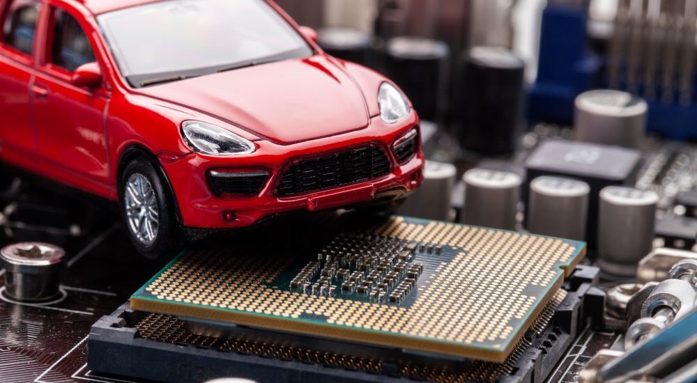 A red toy car is shown on a computer chip.