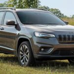 A grey 2020 Jeep Cherokee is shown parked in an open grassy field.