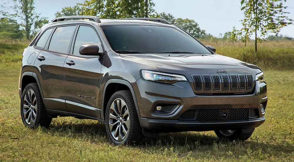 A grey 2020 Jeep Cherokee is shown parked in an open grassy field.